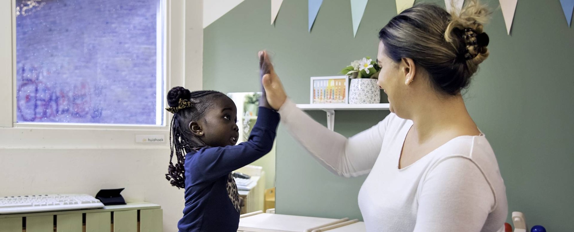 Docente geeft een high five aan een meisje.