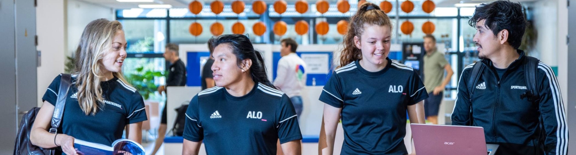 sportkunde en alo samen liggende foto studenten lopen over atletiekbaan binnen bij gymnasion selena esteban carlijn randy 2022