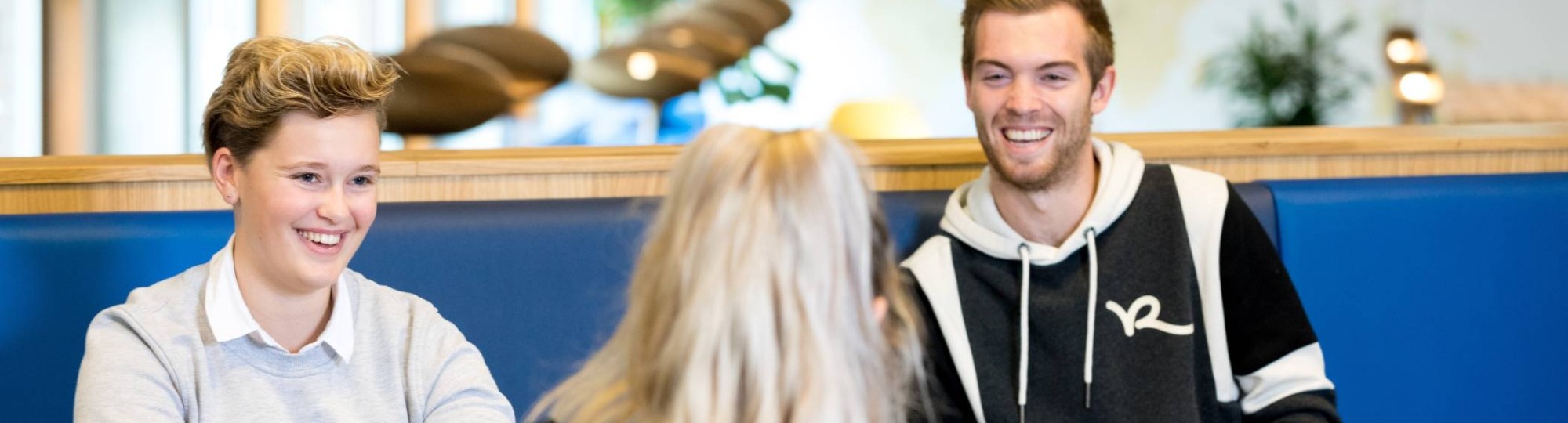 Drie studenten van de HAN Pabo Arnhem zitten bij elkaar en lachen tijdens het studeren.