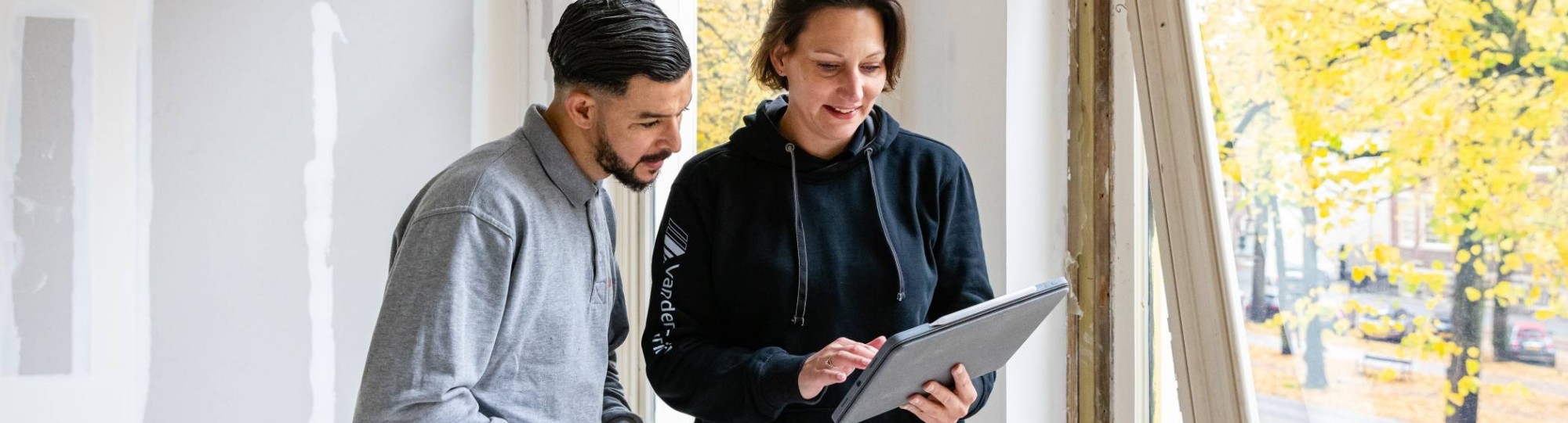 bouwkundige bespreekt bij een venster de voortgang met een medewerker