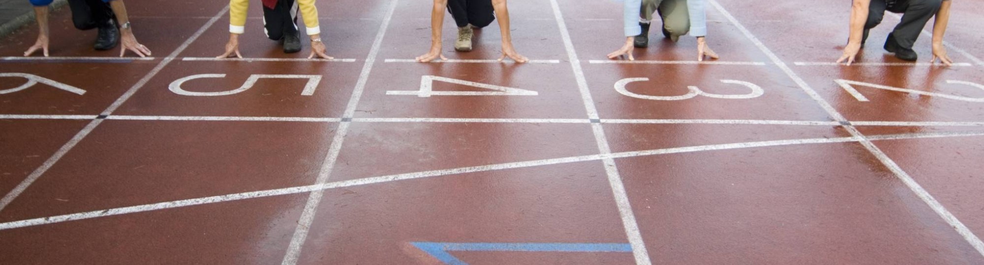 groepje actieve ouderen staat aan de startlijn van een hardloopbaan