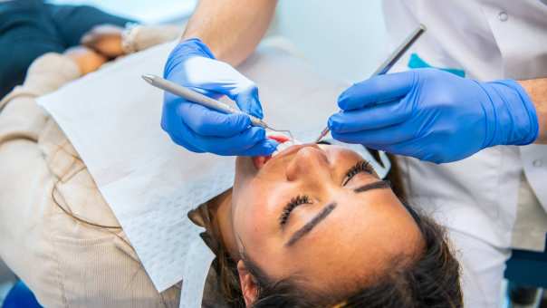 Patient ligt op een behandelstoel met materialen in haar mond.