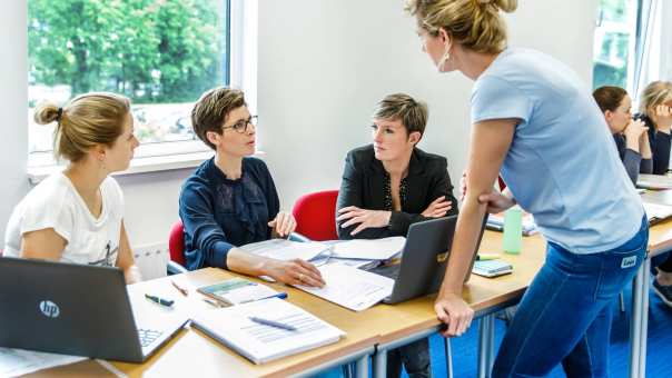 Deeltijd bachelorstudenten tijdens de les in overleg met een docent.