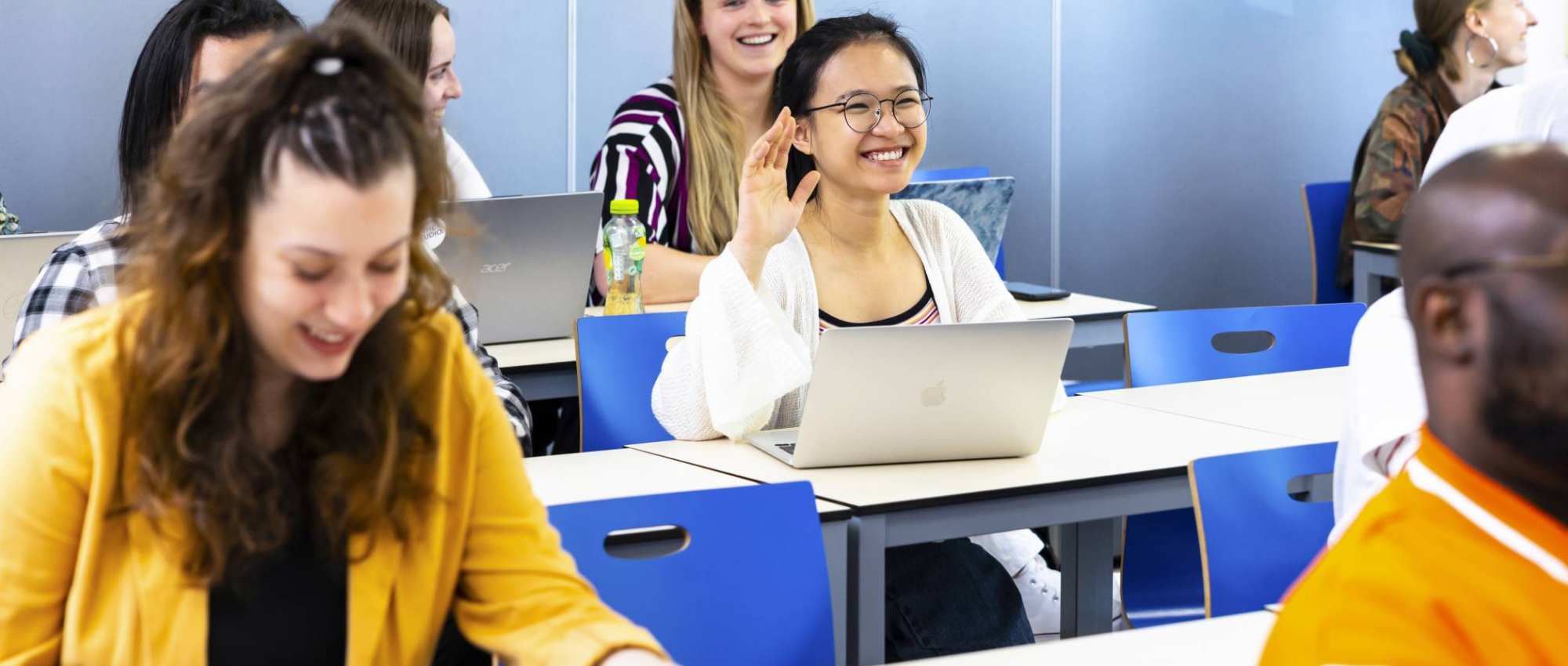 Students in a class, one student puts her hand up