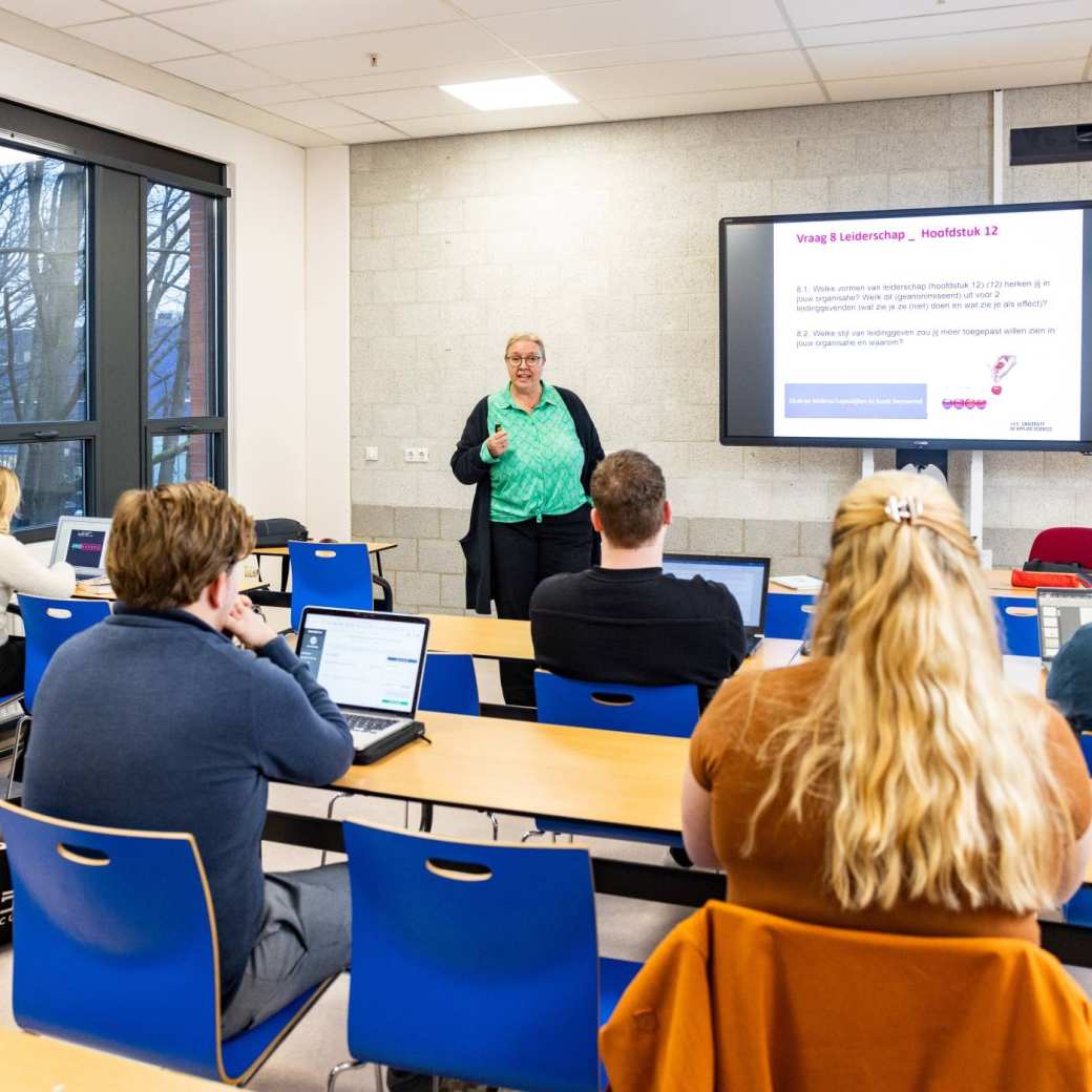 Meerdere studenten van de opleiding logistiek achter een laptop les aan het volgen