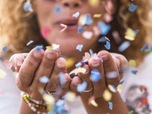 vrouw met confetti in handen en blaast