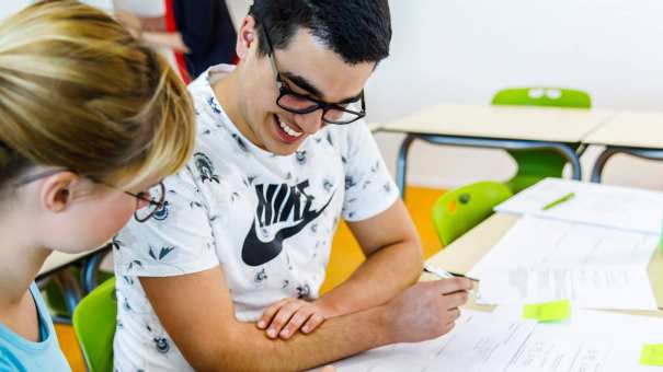 Twee studenten lezen de opdrachten op de werkbladen, die voor hun op de tafel liggen. 