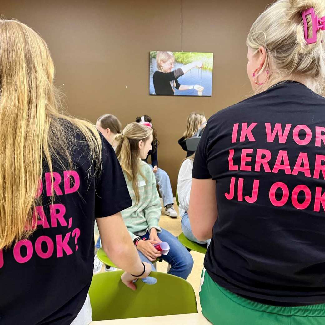 Foto van 2 studenten met een shirt 'ik word leraar, jij ook?', bij de Teachers Experience die op middelbare scholen wordt gedaan onder begeleiding van studenten van onze lerarenopleidingen