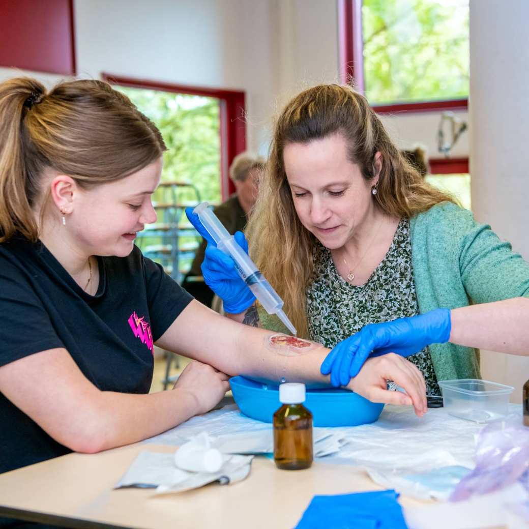 2 studenten zijn tijdens de les Verpleegkunde deeltijd aan het oefenen met wondverzorging, wond schoonmaken