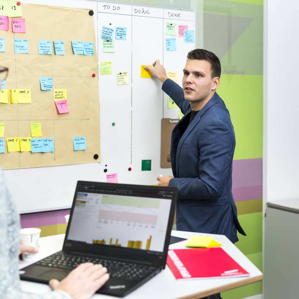 Overleg man en vrouw met laptop en whiteboard in kantoor