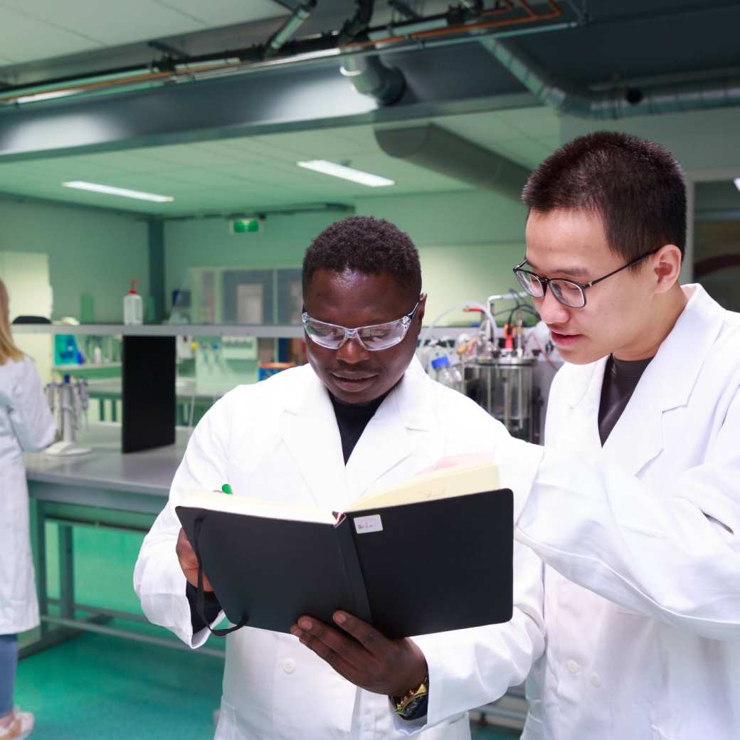 Studenten master Life Sciences Alain Barhasima en Dat Le werken in een biologielab. Op de rug Lisan Scholten