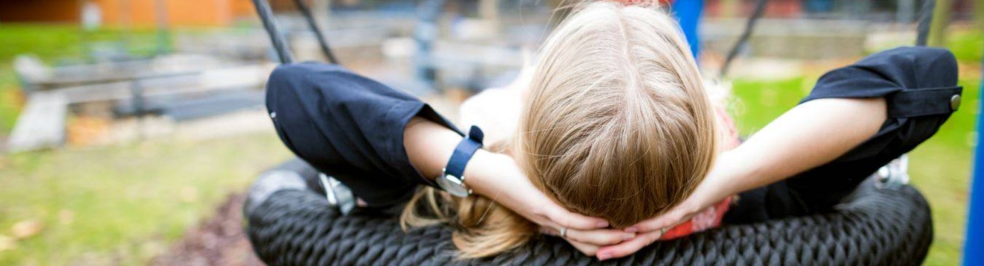 Een foto van student Meike Geurts die zit te relaxen op een schommel in een speeltuin.