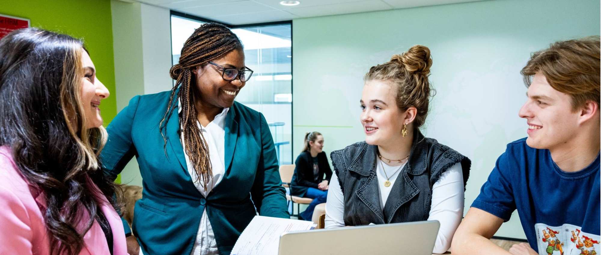 Studenten Human Resource Management (HRM) in gesprek met een docent met een laptop erbij