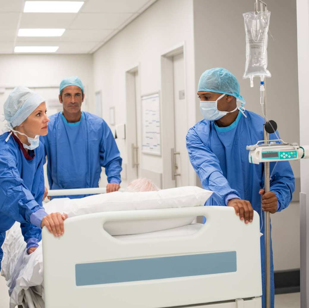 Ziekenhuispersoneel in ziekenhuis duwen een bed met patient