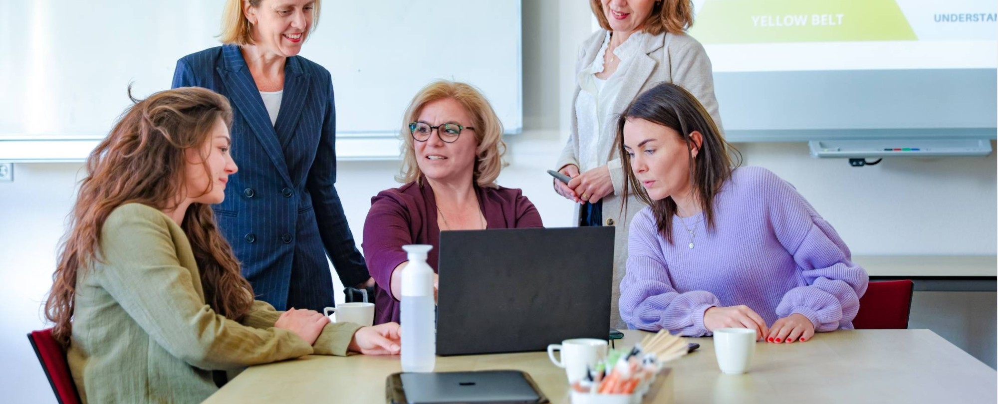 twee personen staan voor het lesbord iets uit te leggen aan vier deelnemers strategisch management