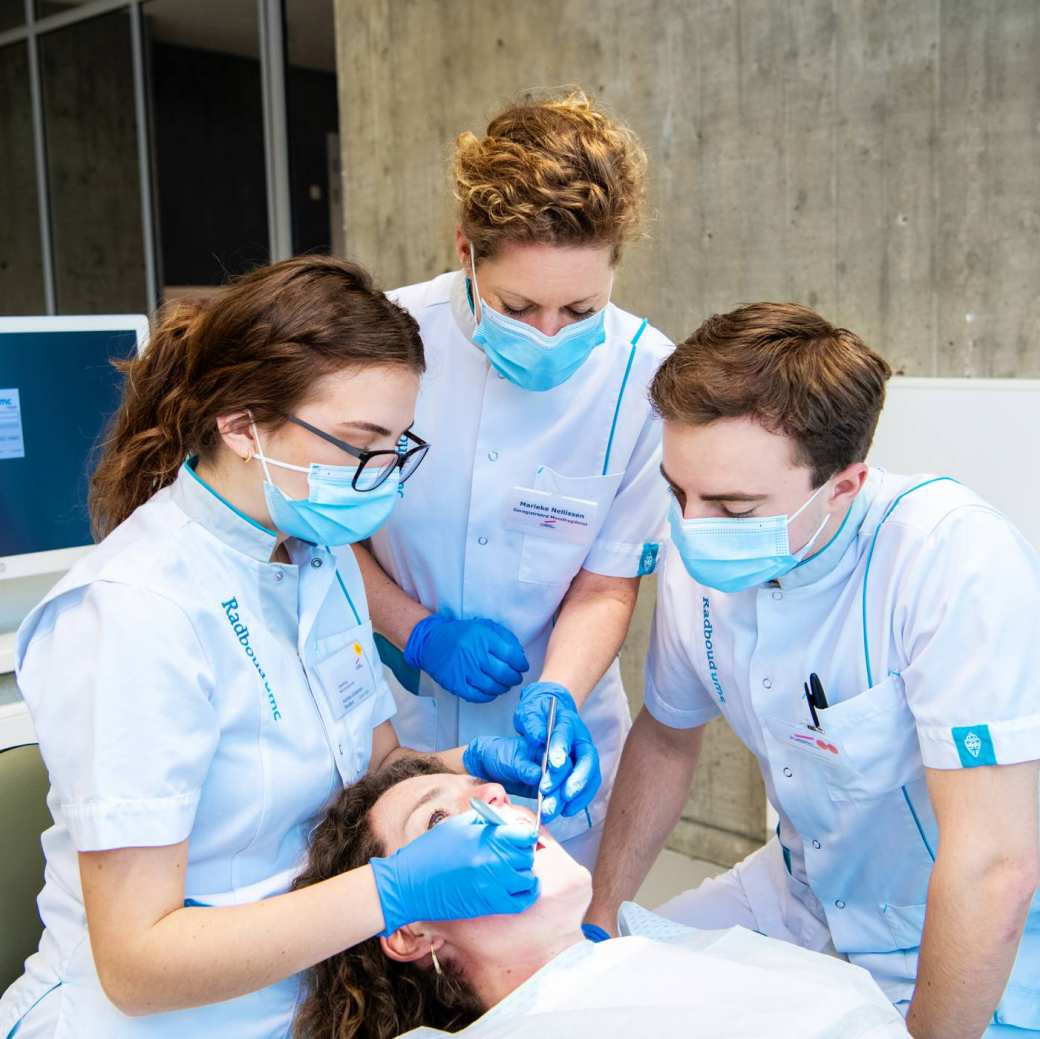 Studenten en docenten Mondzorgkunde kijken in de mond van een patiënt