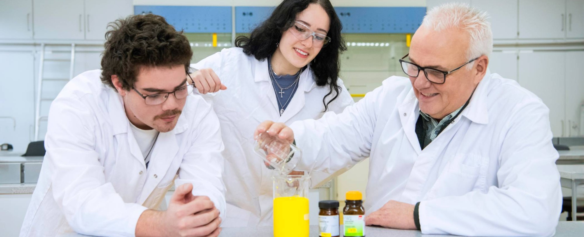 Twee Leraar Scheikunde studenten voeren een proef uit met docent Scheikunde.