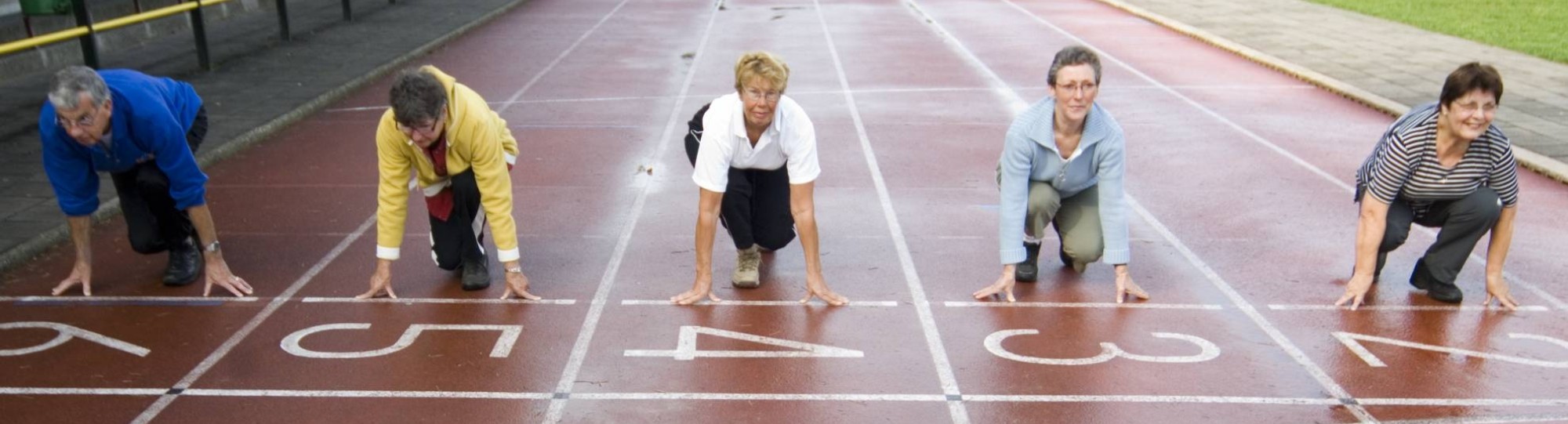 groepje actieve ouderen staat aan de startlijn van een hardloopbaan