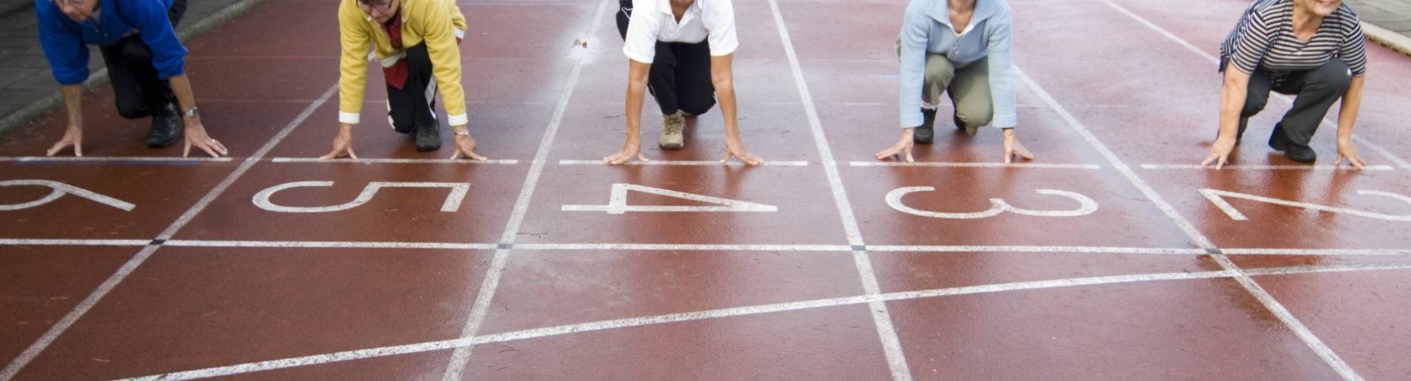 groepje actieve ouderen staat aan de startlijn van een hardloopbaan