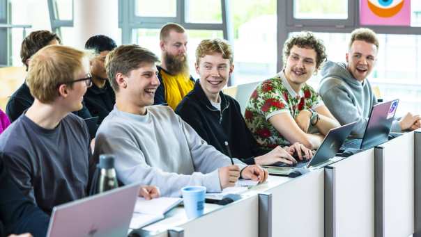 hbo ict studenten zitten lachend in de collegezaal te luisteren naar een docent