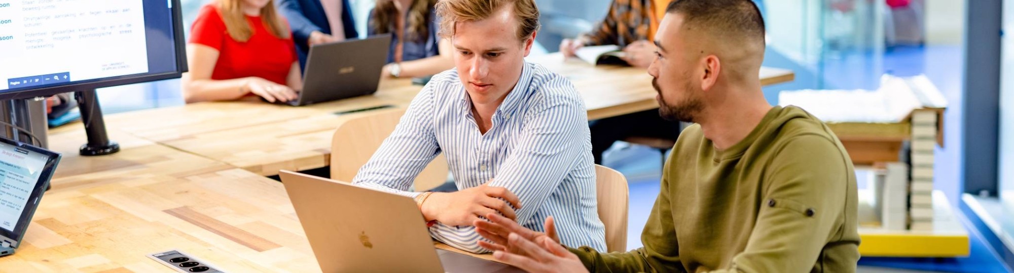 Data science studenten zitten lachend achter een laptop te werken