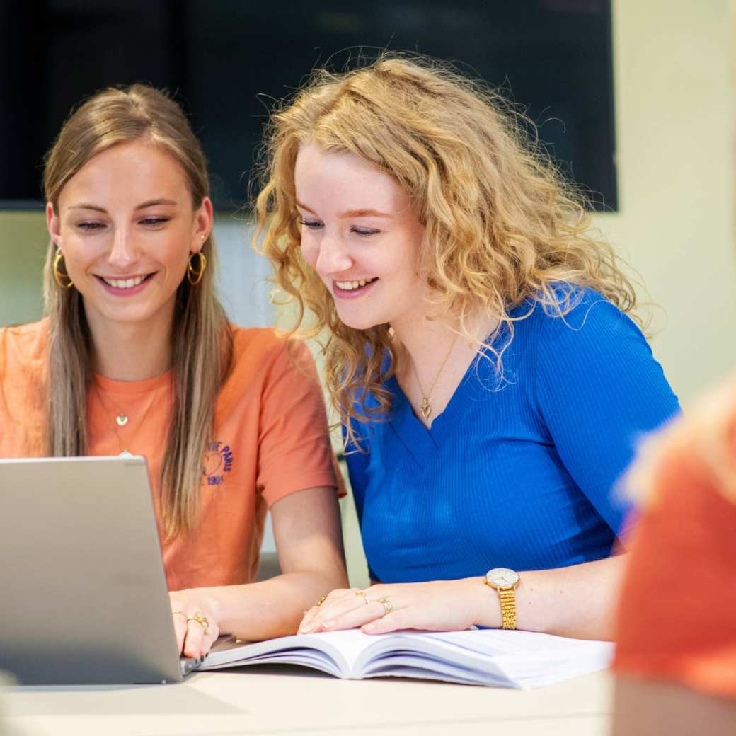 Verpleegkunde studenten drinken samen koffie terwijl ze op hun laptops werken