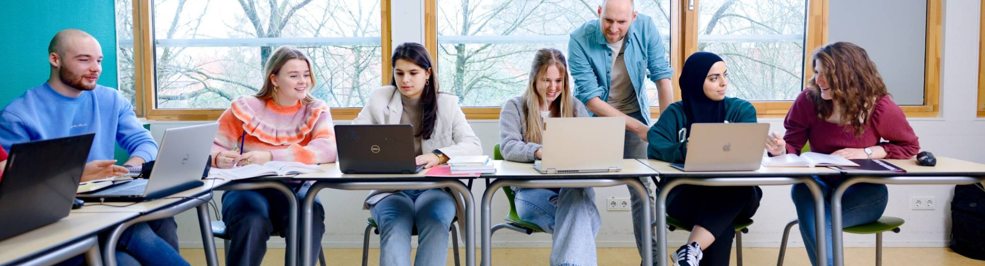 Pabo studenten zitten in de les en docent helpt