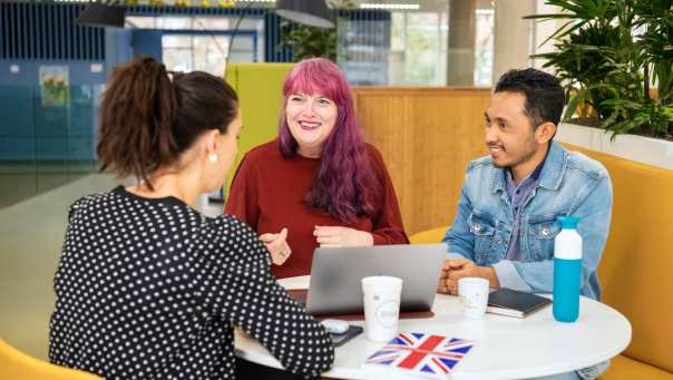 Drie studenten Leraar Engels zitten aan een ronde tafel te overleggen met elkaar.
