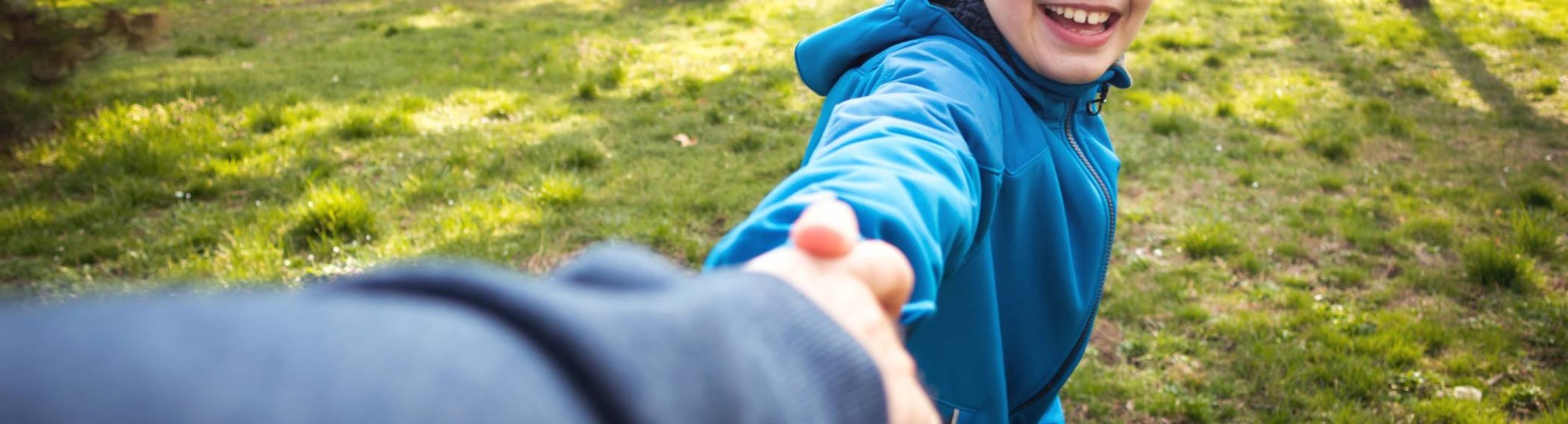 jongen in park die hand van ouder vasthoudt