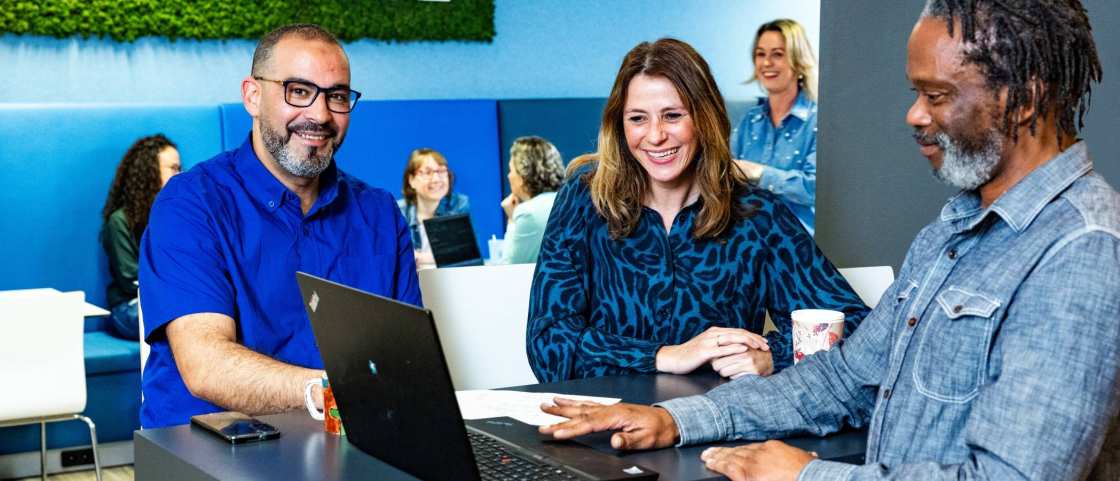 drie mensen overleggen aan een hoge tafel op de HR afdeling