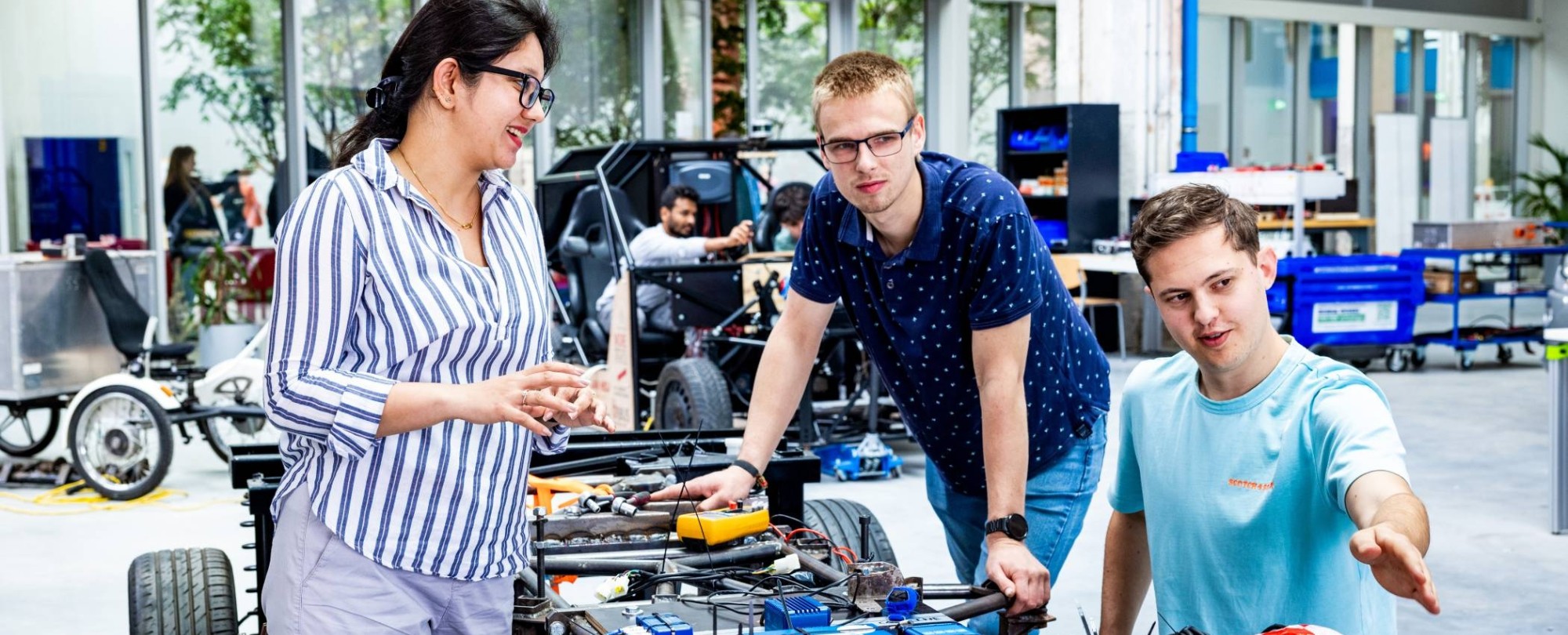 De docent van de Master of Engineering Systems Automotive Systems met twee studenten bij de MORE Vehicle.