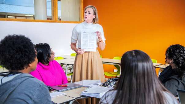 docent met formulier in de hand die ze toont aan de klas met masterstudenten