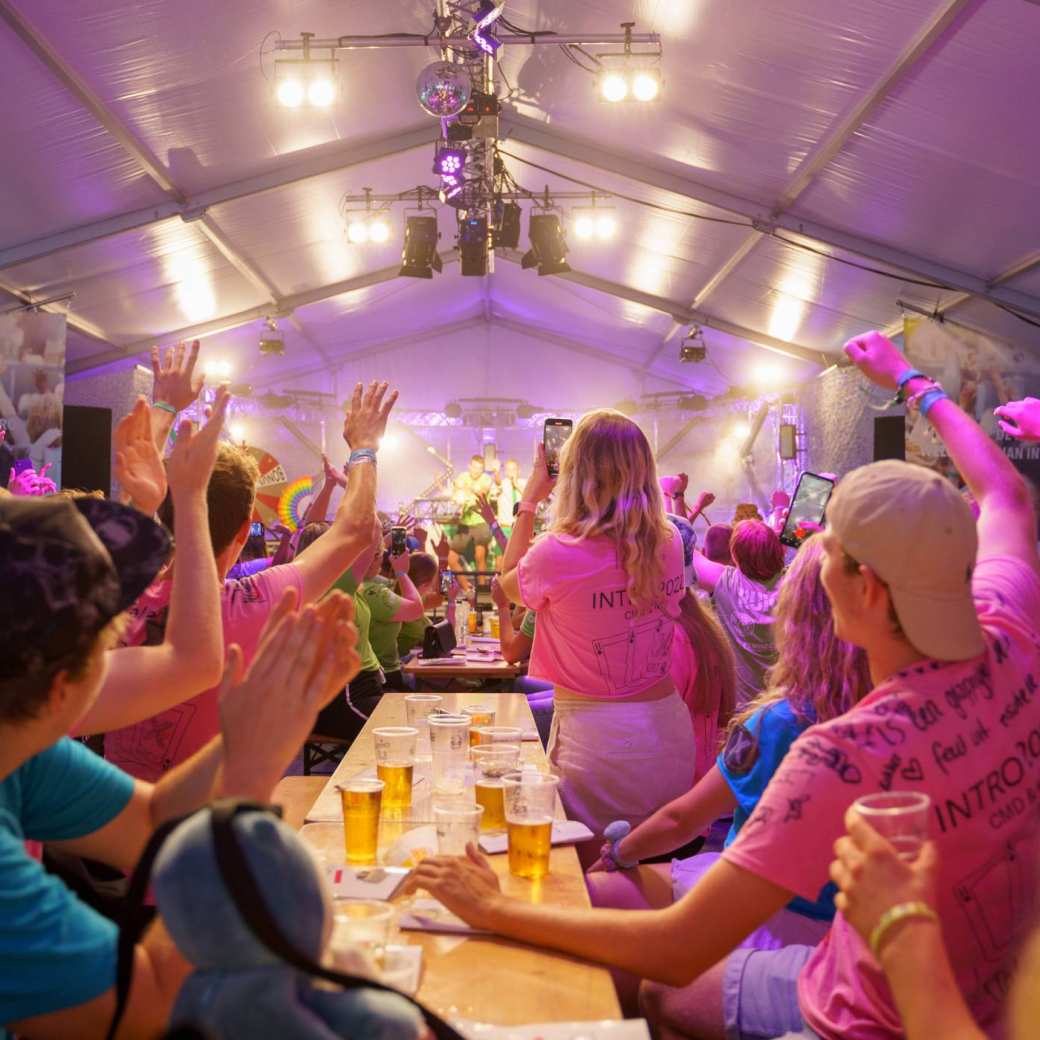 HAN-studenten aan een lange tafel met biertjes in een feesttent.