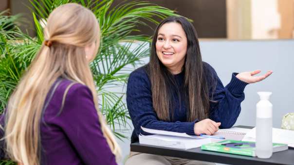 Student legt iets uit en heeft een donkerblauwe trui aan.