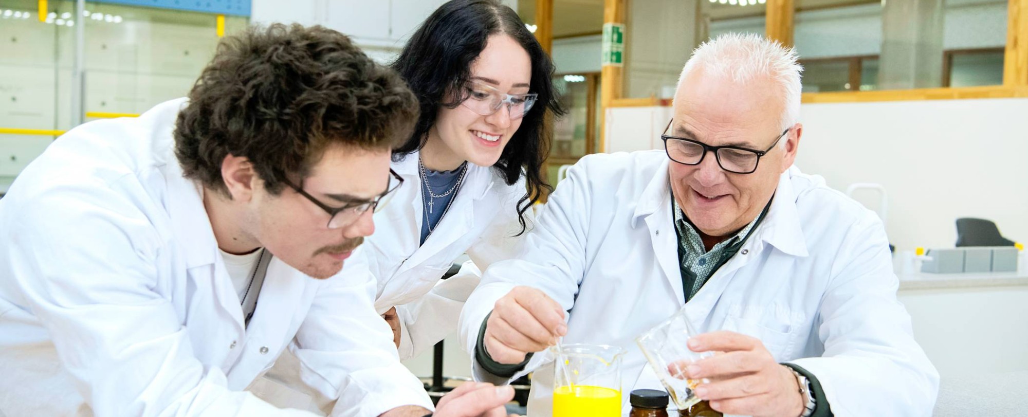 Twee studenten in een labjas kijken aandachtig naar een reageerbuisje.