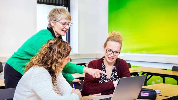 Docent legt lesstof uit aan 2 studenten