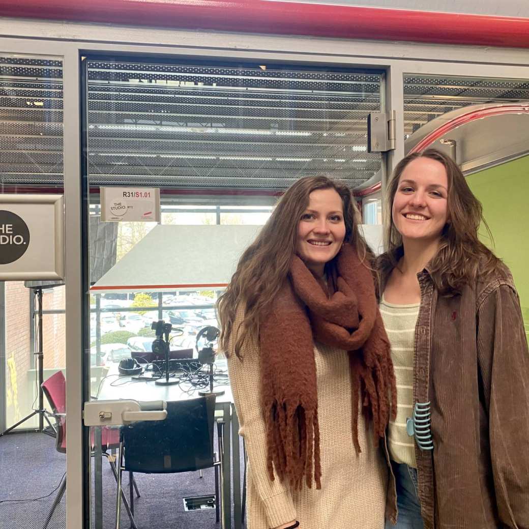 One master student and one employee standing in front of a podcast studio at the HAN University of Applied Sciences