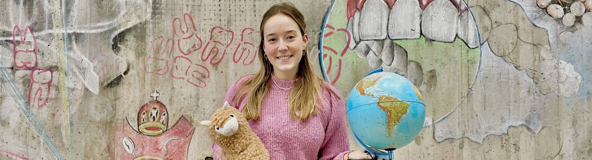 Iris Klein. student Mondzorgkunde met een wereldbol en een knuffel van een lama in haar hand. 