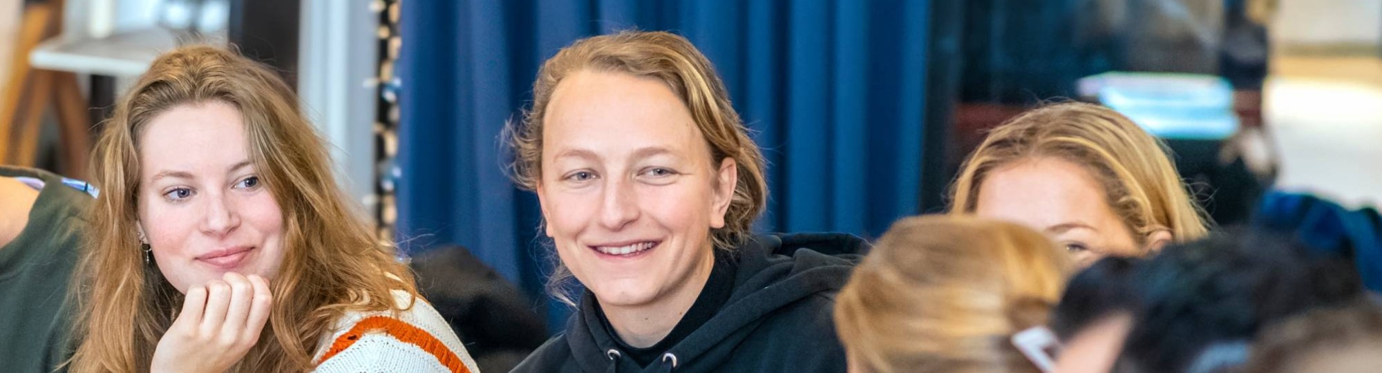 Studenten zitten samen, lachen met elkaar.