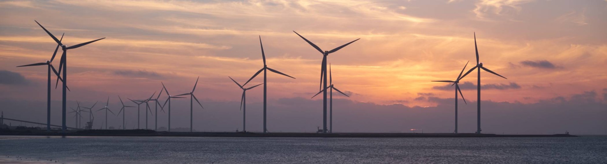 Windmolens bij ondergaande zon in zee