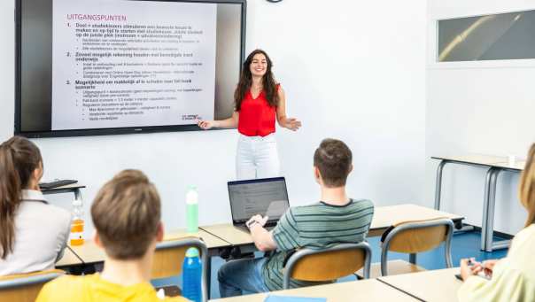 Studente geeft presentatie aan medestudenten in leslokaal. 