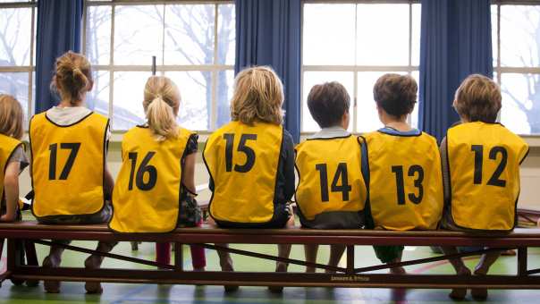 in een gymzaal met hesjes aan op de rug gefotografeerd