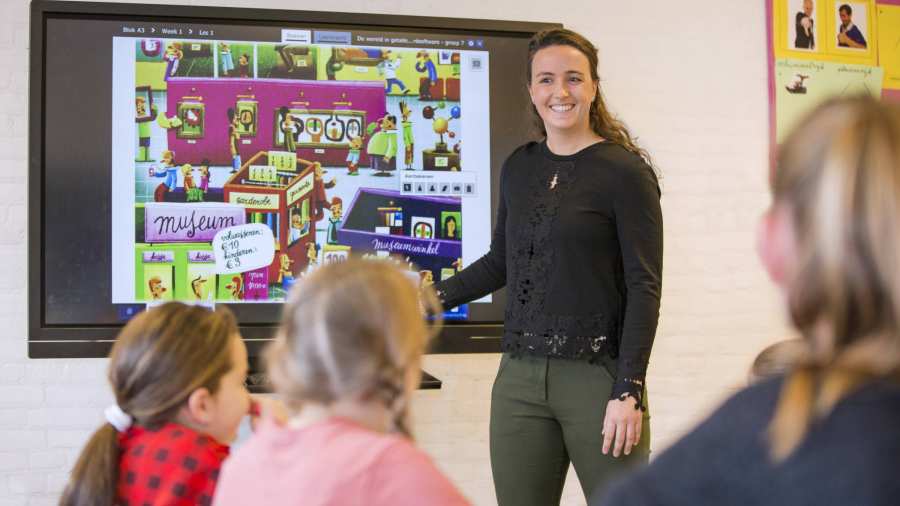 Pabo-docente geeft les aan haar klas en gebruikt daarbij een groot beeldscherm.