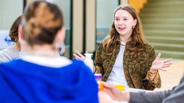 De student vertelt met twee handen in de lucht. 