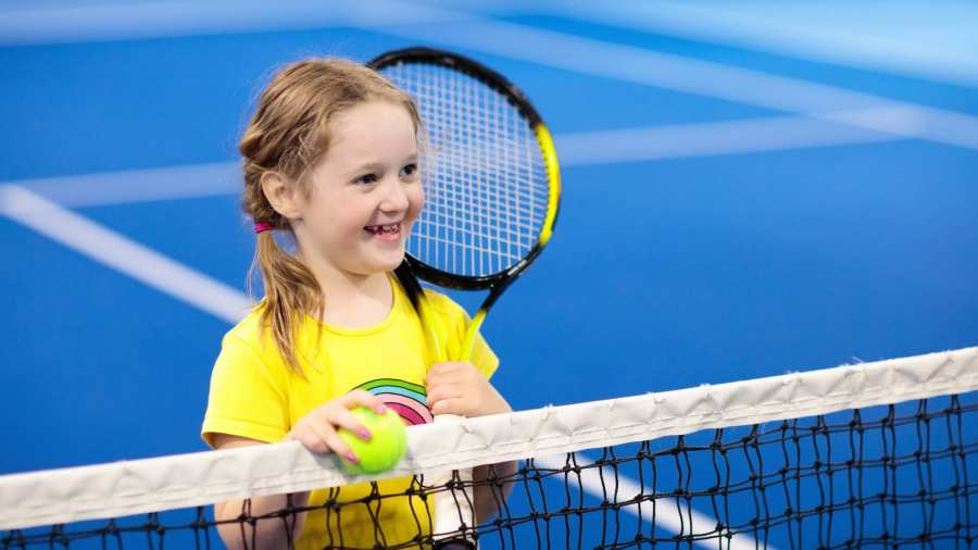 kind bij tennisnet op indoor baan