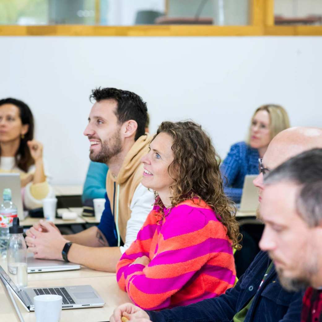 Foto van Master Ontwerpen van Eigentijds Leren. Masterstudenten zitten achter hun bureau en luisteren aandachtig. 