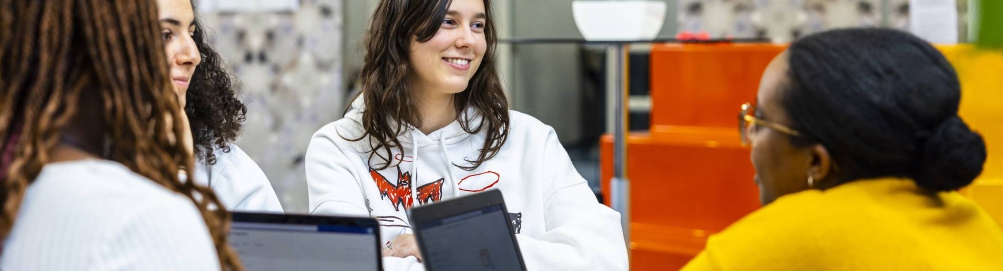 International Social Work. Groepje studenten lachend in een loungebank met laptops op tafel