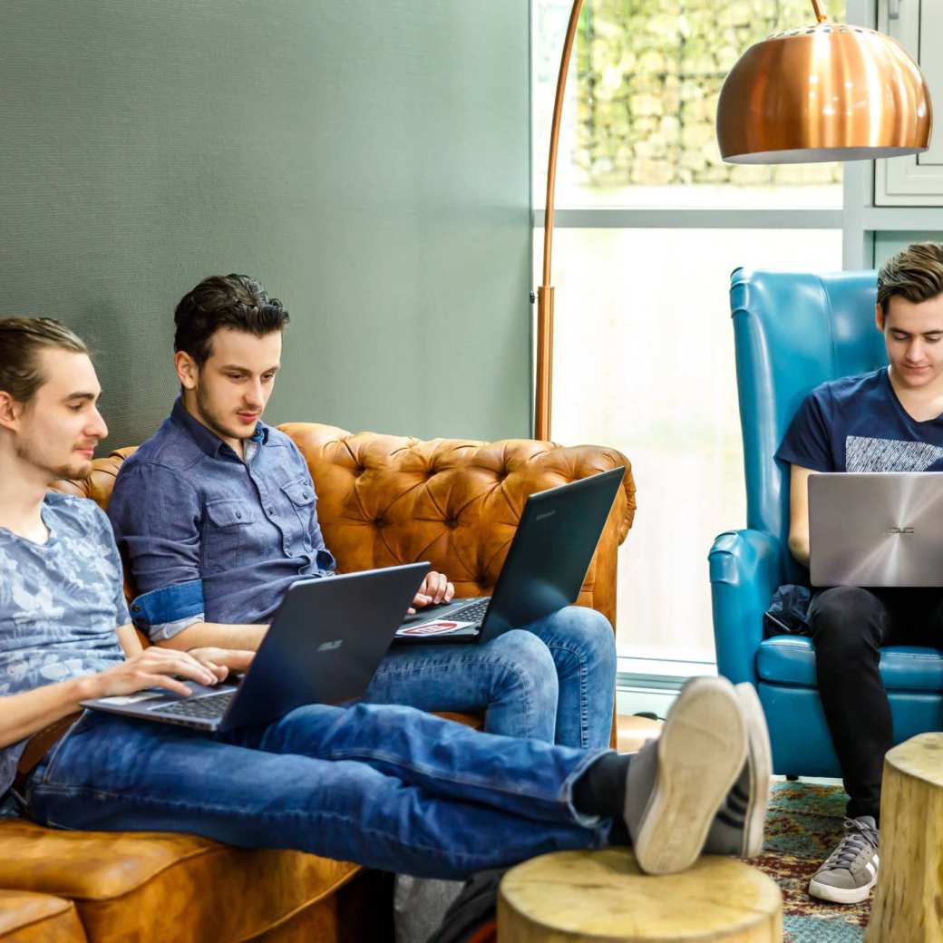 Drie jongens werken op laptop in huiskamer zitje