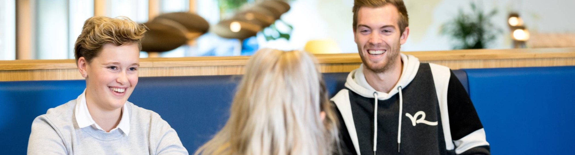 Drie studenten van de HAN Pabo Arnhem zitten bij elkaar en lachen tijdens het studeren.