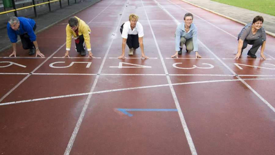 groepje actieve ouderen staat aan de startlijn van een hardloopbaan